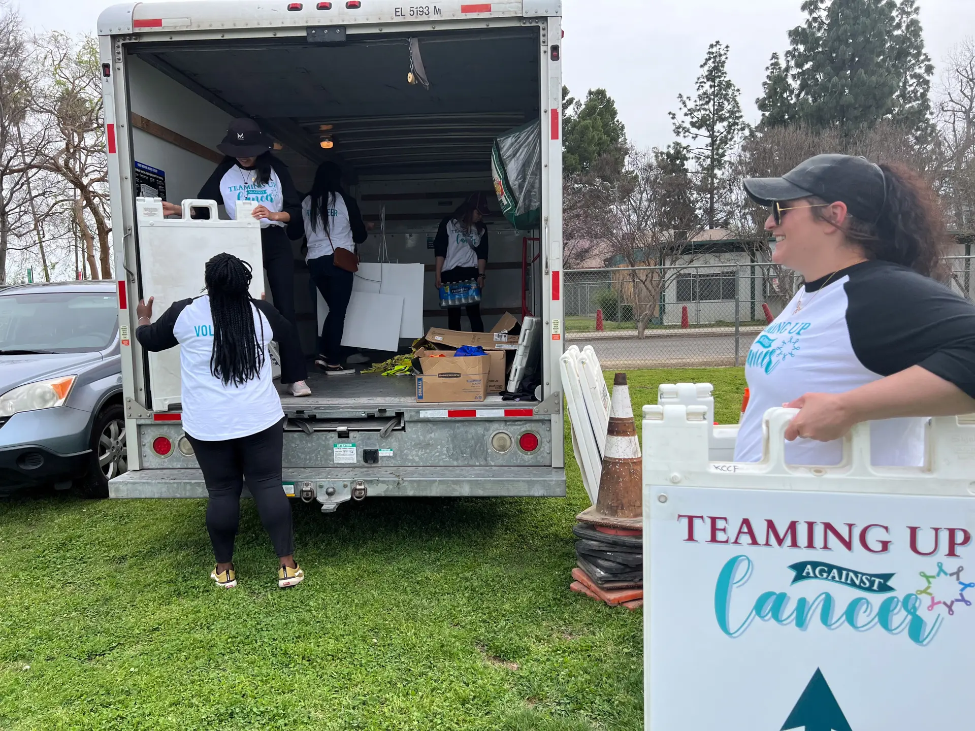 Teaming Up Against Cancer volunteers unloading signage from a moving truck