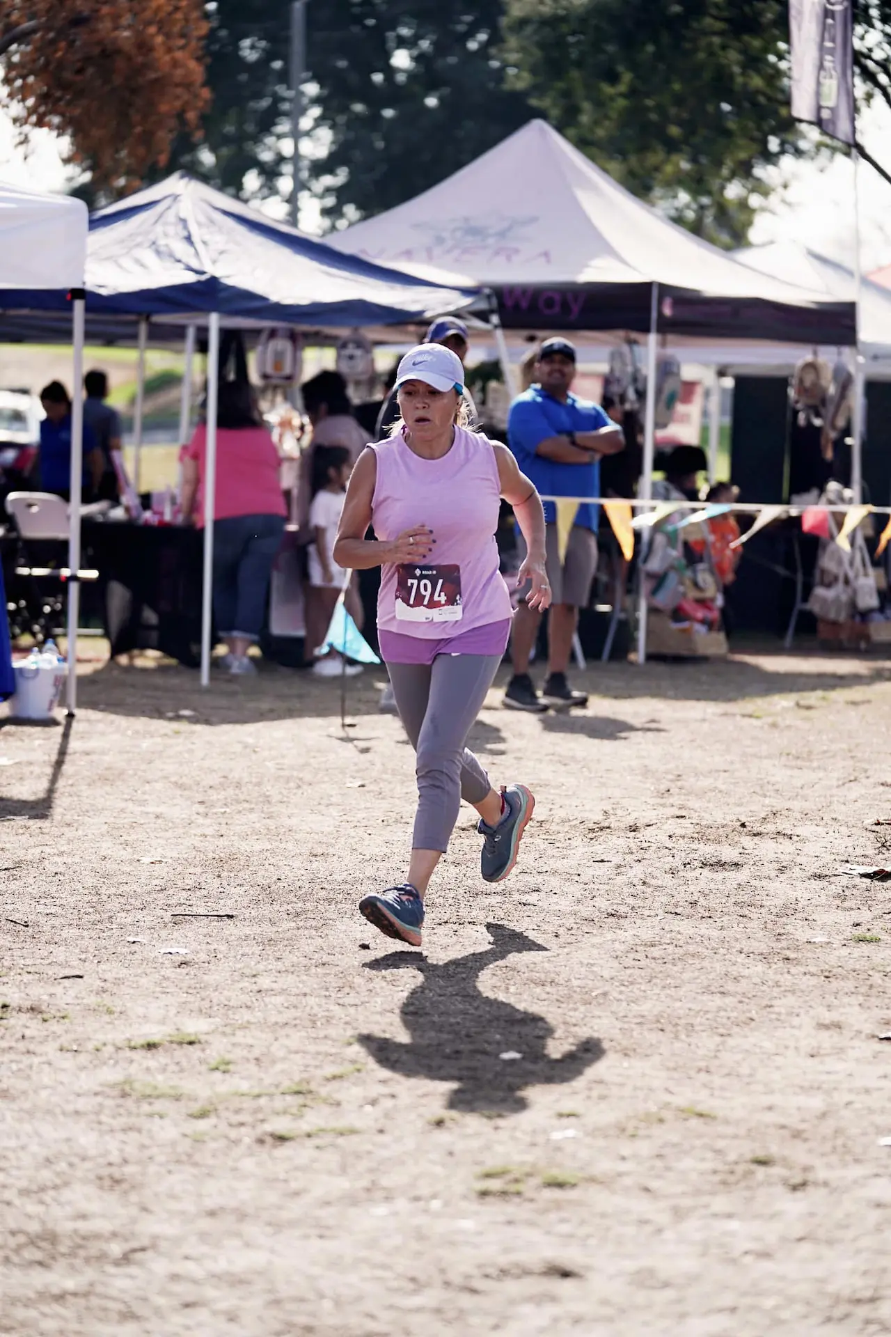 A woman in a white hat and pink top running at Kern Run Walk