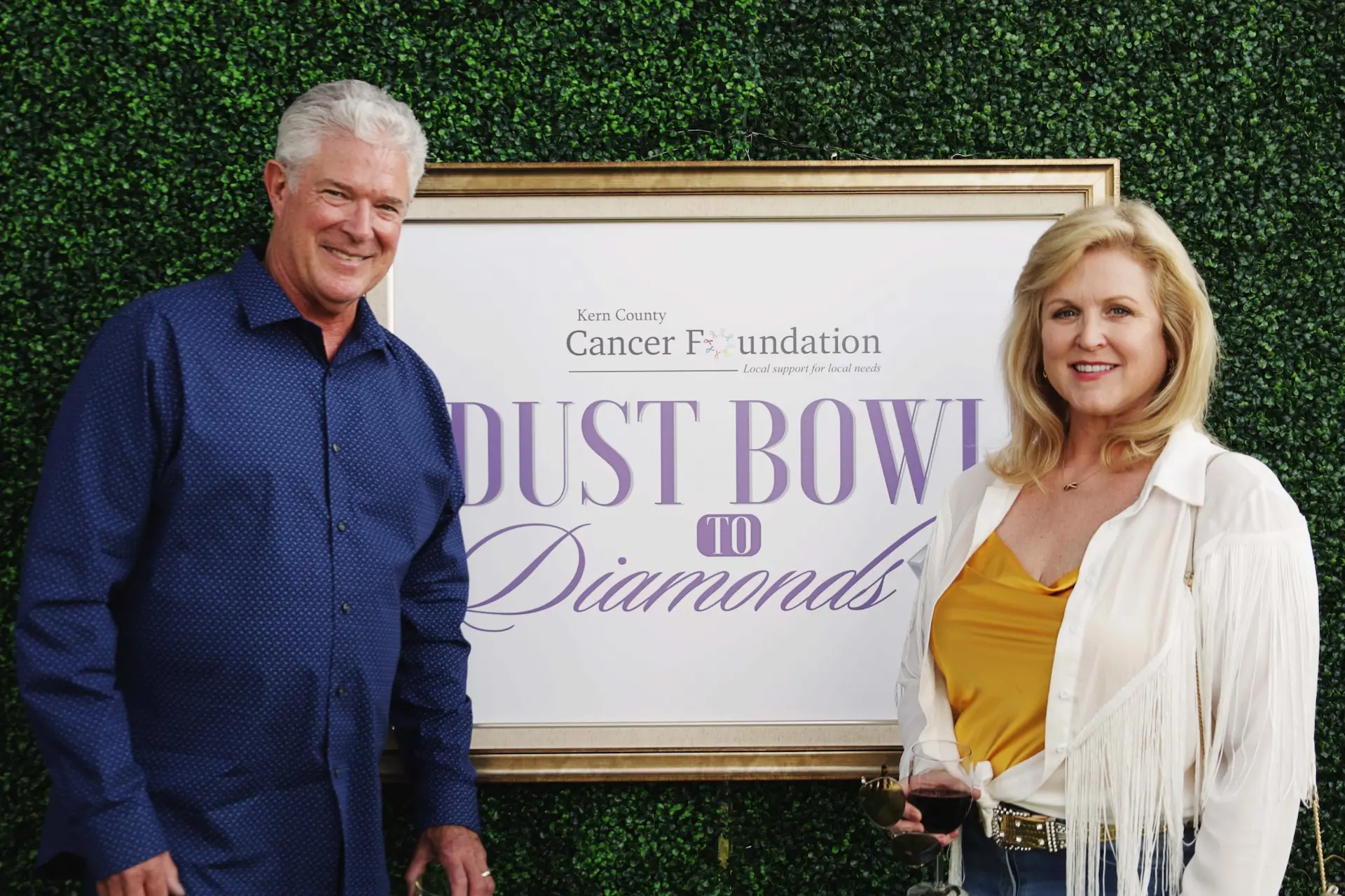 A couple posing in front of the Dust Bowl to Diamonds signage